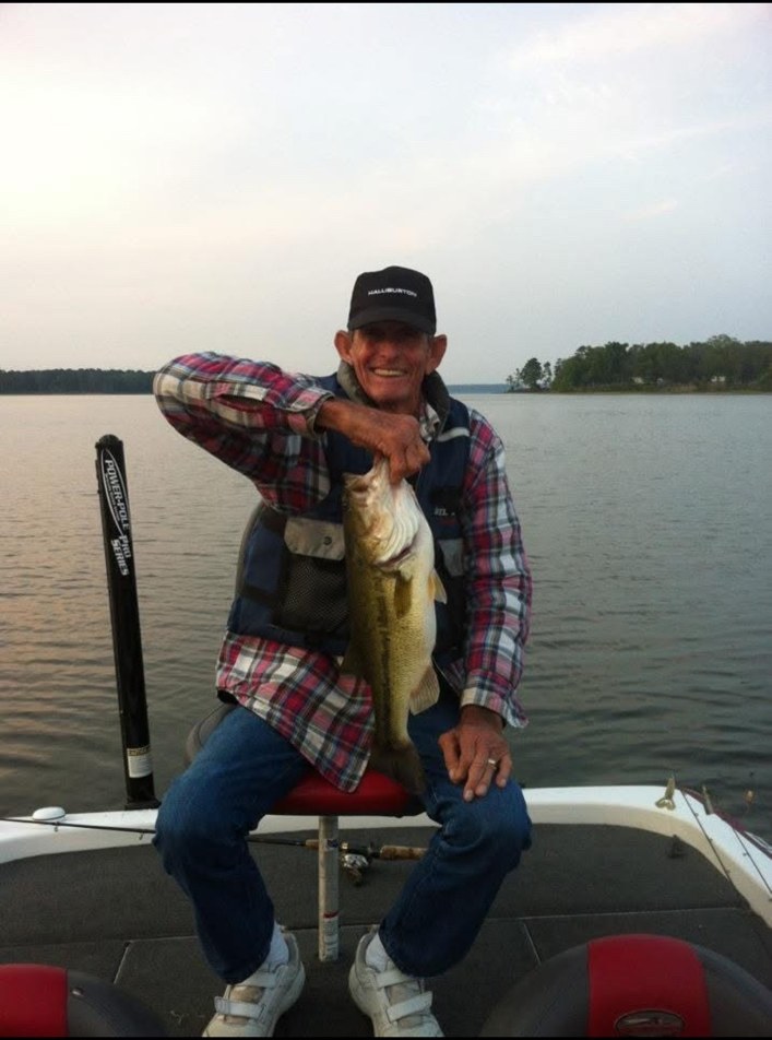 Brad Smith holding a largemouth bass while seated on his fishing boat